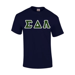 May include: Navy blue t-shirt with the Greek letters Sigma, Delta, and Lambda in green with a white outline. The shirt is a short-sleeved crew neck style.