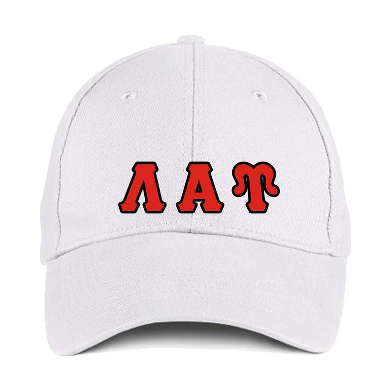 May include: A white baseball cap featuring the letters "AAT" in red with a black border. The cap has a curved peak and a rounded crown, suitable for casual wear.