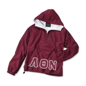 May include: Maroon hooded anorak jacket with a white interior lining. The jacket features a half-zip closure, a front pocket, and the word "ΛON" in white block letters. The drawstring at the bottom allows for an adjustable fit.
