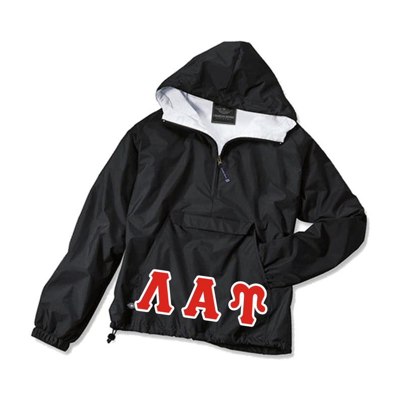 Puede incluir: Chaqueta anorak negra con capucha y forro interior blanco. Cuenta con cremallera parcial, bolsillo delantero y cord&oacute;n en el dobladillo. Las letras "&Lambda;&Alpha;&Tau;" en rojo est&aacute;n impresas en la parte inferior delantera.