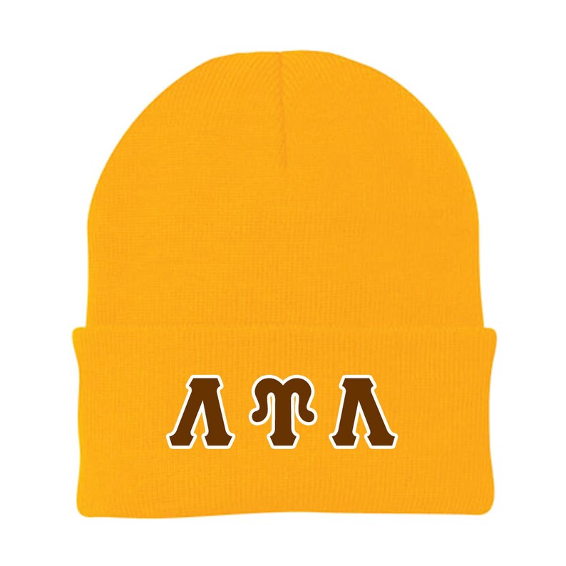 K&ouml;nnte beinhalten: Eine gelbe Strickm&uuml;tze mit einem braunen gestickten griechischen Buchstabenmuster, das "&Lambda;&Pi;&Lambda;" lautet.