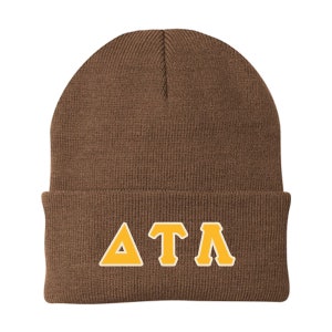 May include: A brown beanie hat with the Greek letters "ΔΤΛ" in gold with a white outline. The hat is made of a knitted material and has a folded brim. The letters are centered on the front of the hat.