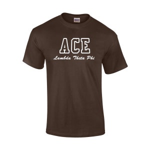 May include: A brown t-shirt with the word "ACE" in white block letters with a white outline. Below the word "ACE" is the text "Lambda Theta Phi" in a cursive font. The shirt is made of a soft material.