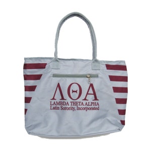 May include: A gray tote bag with red and white stripes. The bag has a zippered pocket on the front and the letters "ΛΘΑ" in maroon with the text "Lambda Theta Alpha Latin Sorority, Incorporated" below.