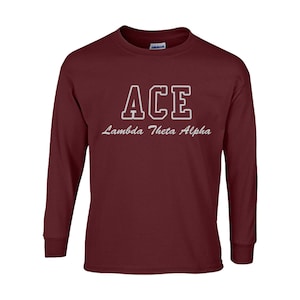 May include: A maroon long-sleeve shirt with the word "ACE" in white block letters and the text "Lambda Theta Alpha" in a cursive font. The shirt is made of a soft material.