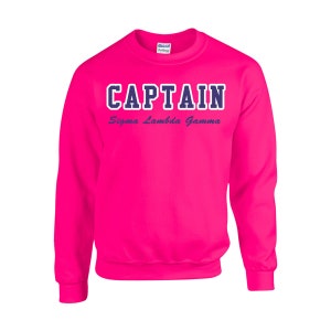 May include: A pink sweatshirt with the text "CAPTAIN Sigma Lambda Gamma" in navy blue and purple lettering.