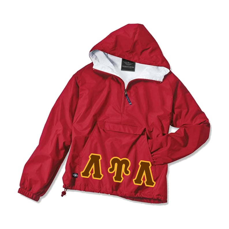 May include: A red hooded anorak jacket with a white interior lining and a front pocket. The jacket features a half-zip closure and the letters "ATA" in a gold and brown design across the front. The jacket is made of a lightweight, water-resistant material.