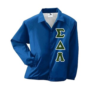 May include: A royal blue coach's jacket with a white interior lining. The jacket features three Greek letters in a green and white design on the front. The jacket has a button-up closure and two front pockets.