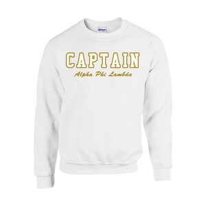 May include: White sweatshirt with the text "CAPTAIN" in gold outlined letters and "Alpha Phi Lambda" in gold script below.