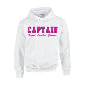 May include: White hooded sweatshirt with the word "CAPTAIN" in pink block letters with a dark pink outline. Below the word "CAPTAIN" is the text "Sigma Lambda Gamma" in pink script.