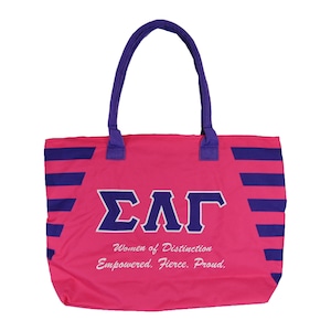 May include: Pink tote bag with purple stripes and the letters "ΣΑΓ" in white with a purple outline. The text "Women of Distinction Empowered. Fierce. Proud." is printed in white below the letters.