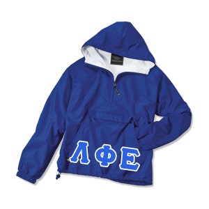 May include: A royal blue hooded anorak jacket with a white interior lining. The jacket features a front pocket, a half-zip closure, and the Greek letters ΛΦΕ in white with a blue outline on the front.