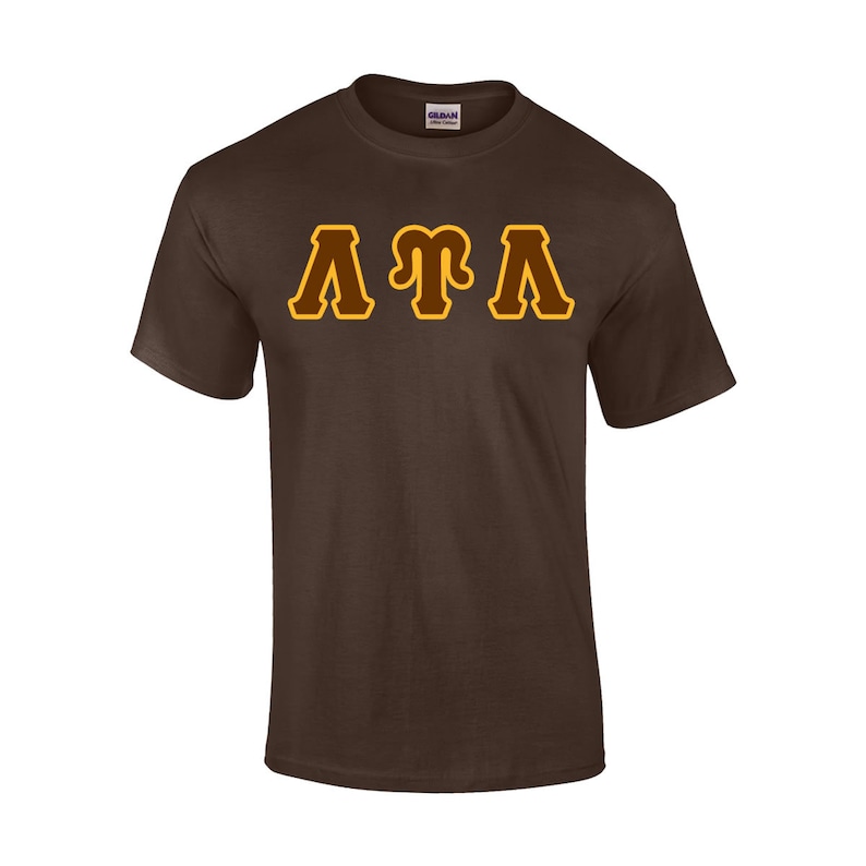 May include: A brown t-shirt with the letters "ATA" in a gold and brown design across the chest. The shirt is made of a soft material and has short sleeves.