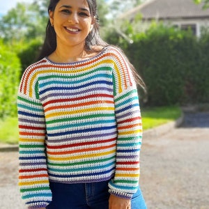 May include: A rainbow striped crochet sweater with long sleeves and a relaxed fit. The sweater is made with a variety of colors, including red, orange, yellow, green, blue, indigo, and violet.