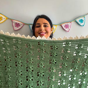 a young woman holding a flower blanket in green