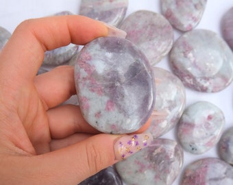 May include: A collection of smooth, polished, pink and grey Lepidolite palm stones. The stones have a natural, marbled appearance with a variety of shades of pink and grey.