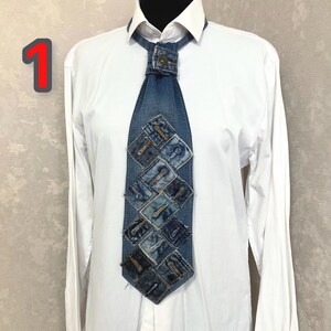 May include: A necktie constructed from blue denim fabric featuring a patchwork design of square denim pieces, each with a visible buttonhole. The tie is secured at the collar with a metal button and is worn over a crisp white long-sleeve button-down shirt.