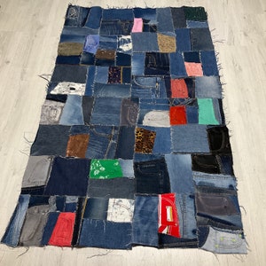 Puede incluir: Una gran alfombra de patchwork hecha de tela vaquera en varios tonos de azul. La alfombra está compuesta por muchos cuadrados de mezclilla de diferentes tamaños, cada uno con un patrón o textura diferente. La alfombra es una forma única y elegante de agregar un toque de encanto rústico a cualquier habitación.