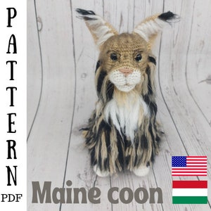 May include: Crochet pattern for a Maine Coon cat. The pattern is available as a PDF download. The image shows a crocheted Maine Coon cat with brown, black, and white fur. The cat is sitting on a wooden surface.