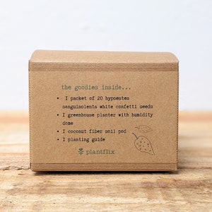 May include: A brown cardboard box with the text "the goodies inside..." listing contents: seeds, a greenhouse planter, a soil pod, and a planting guide. The brand name "plantflix" is at the bottom.