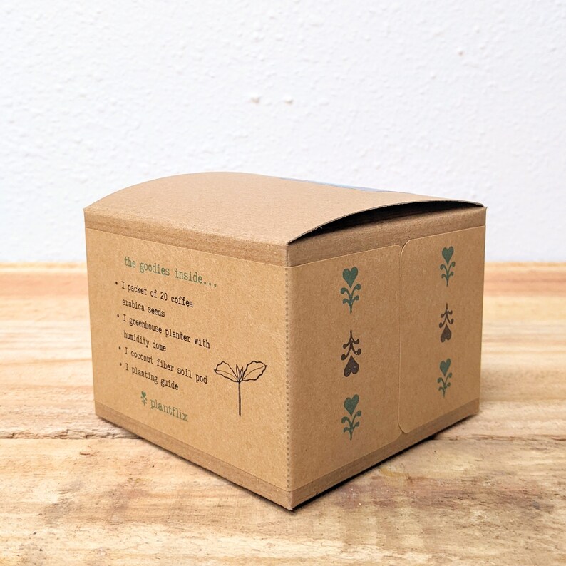K&ouml;nnte beinhalten: Eine braune Pappschachtel mit dem Text "the goodies inside..." und einer Inhaltsliste, einschlie&szlig;lich Kaffeesamen und einer Pflanzanleitung. Die Schachtel hat gr&uuml;ne und braune dekorative Blumendesigns und das "plantflix"-Logo.