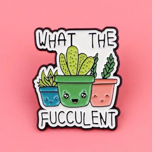 Peut inclure: Une broche en émail blanc représentant trois succulentes en pot de dessin animé avec des visages souriants. Le pot vert central contient un cactus, flanqué d'un pot bleu et d'un pot rose. Le texte WHAT THE FUCCULENT est écrit en lettres noires.