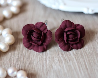 May include: A pair of burgundy rose-shaped earrings with silver hooks.