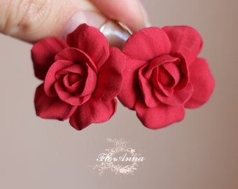 May include: A pair of red rose-shaped earrings. The earrings are made of polymer clay and have a realistic look.