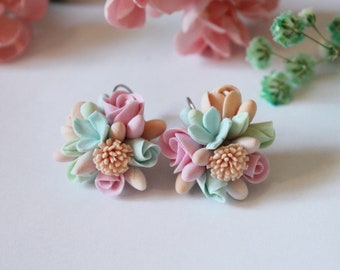 May include: A pair of pastel-colored polymer clay earrings featuring a cluster of small flowers in shades of pink, peach, and light blue.