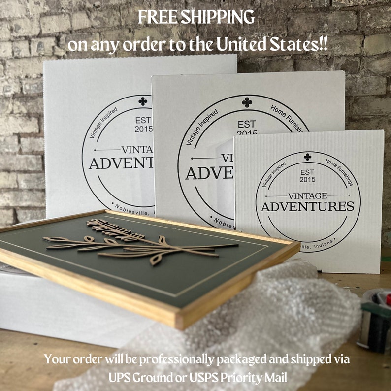 May include: Three white cardboard boxes with black text and logos. The boxes are stacked on top of each other. The top box has the text "Vintage Inspired" and "EST 2015" and the logo "Vintage Adventures". The middle box has the text "Vintage Inspired" and "EST 2015" and the logo "Vintage Adventures". The bottom box has the text "Home Furnishings" and "EST 2015" and the logo "Vintage Adventures".