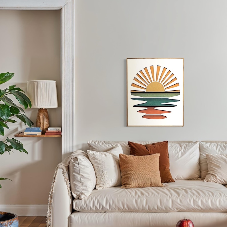 May include: A framed print of a sunset over a body of water. The sun is depicted as a yellow circle with orange rays emanating from it. The water is represented by a series of blue, green, and orange stripes.