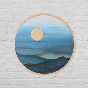 May include: A round wooden wall art piece with a blue and white gradient sky and a light wood moon. The bottom of the piece features a dark blue and green mountain range.