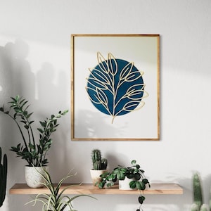 May include: A framed wall art piece featuring a gold leaf design on a blue circle background. The design is a stylized branch with leaves.