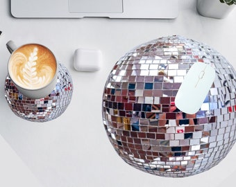 May include: A silver disco ball mousepad with a white wireless mouse on top. The mousepad is on a white surface.