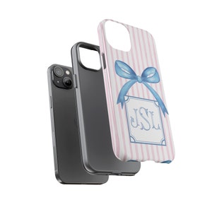 K&ouml;nnte beinhalten: Eine rosa-wei&szlig;e gestreifte Handyh&uuml;lle mit einer blauen Schleife und einem monogrammierten Rechteck mit der Aufschrift "JSL".