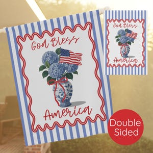 May include: Double-sided garden flag with a patriotic design. Features a blue and white striped background with a white center. The center displays a floral arrangement in a blue and white vase, an American flag, and the words "God Bless America."