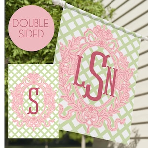 May include: Double-sided garden flag with a light green and white diamond pattern. The flag displays a pink floral frame with the letters "LSN" in the centre. A smaller version of the flag is shown on the left, with the letter "S".