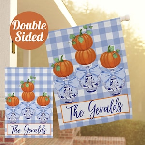 May include: Double-sided outdoor flag with a blue and white gingham pattern. The flag features orange pumpkins stacked on blue and white vases with bows. The text "The Geralds" is displayed on the bottom.
