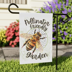 May include: A white garden flag with a watercolor illustration of a bee and the text "Pollinator Friendly Garden".