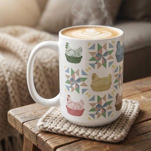 May include: White ceramic mug with a handle, decorated with chickens in baskets and geometric patterns. The mug contains a latte, and sits on a knitted coaster, placed on a wooden surface.