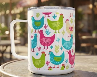 May include: White travel mug with a handle, featuring a repeating pattern of colorful chickens in teal, pink, green, and yellow. The design includes leaf and floral accents. The mug is sitting on a metal table.