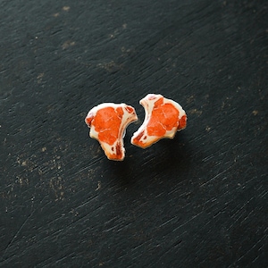 May include: Two red and white fabric earrings shaped like a steak.