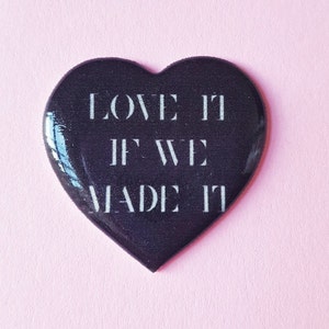 May include: Black heart-shaped pin with the text "LOVE IT IF WE MADE IT" in white lettering.