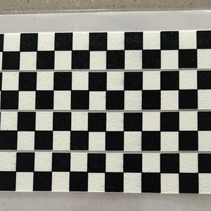 May include: A black and white checkered pattern printed on a white surface. The pattern is made up of squares, and there are four rows of squares.