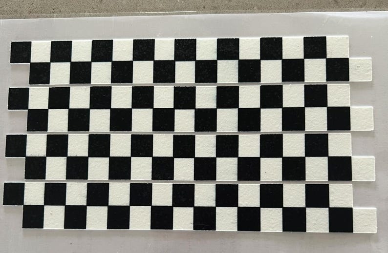 May include: A black and white checkered pattern printed on a white surface. The pattern is made up of squares, and there are four rows of squares.