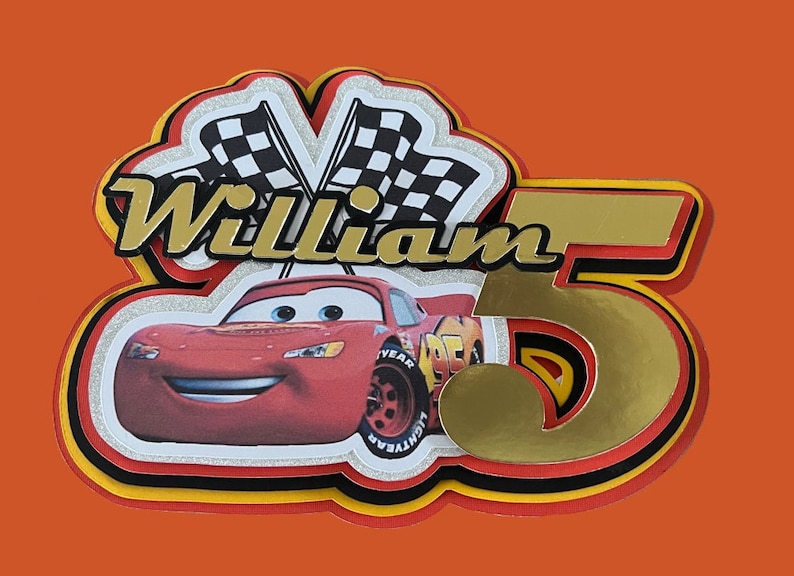 May include: A red race car with a smiling face, a gold number 5, and the name "William" in gold letters. The car is surrounded by checkered flags and a red, yellow, and black border.