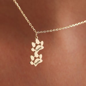 May include: Gold necklace with two paw print charms, each engraved with a dog's name: Daisy and Sadie.