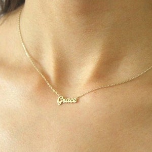 May include: A gold chain necklace with a delicate pendant that reads "Grace".
