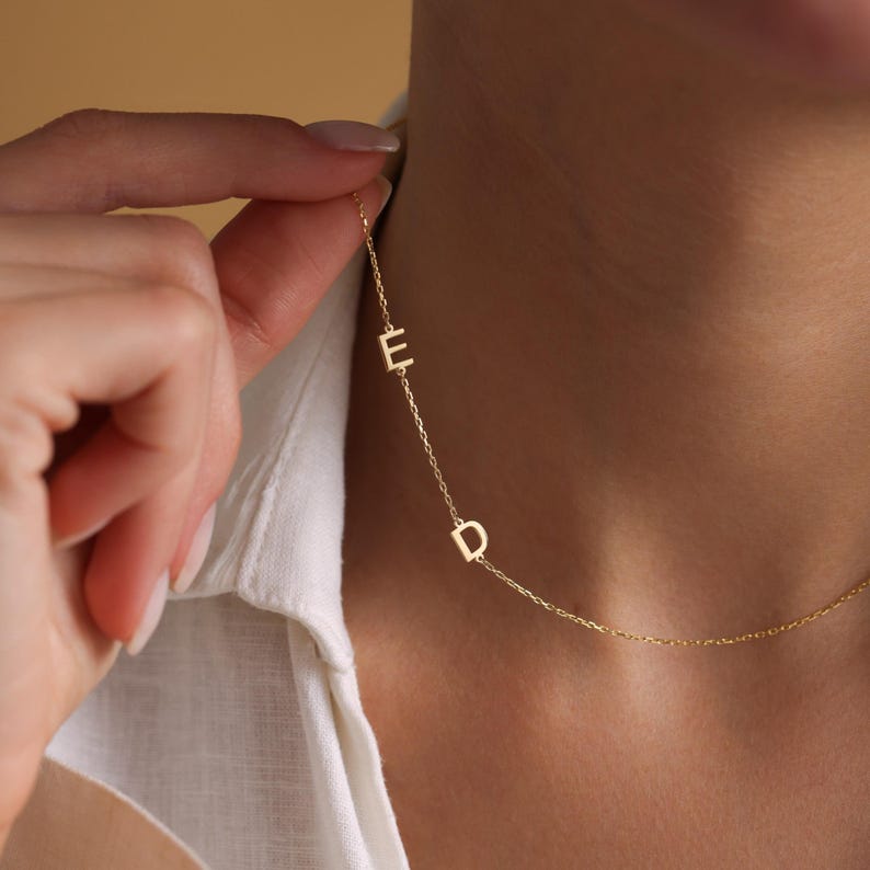 May include: A gold chain necklace with the letters "E" and "D" hanging from it.