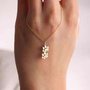 May include: Gold necklace with a paw print charm. The charm has the names "Daisy" and "Sadie" engraved on it.